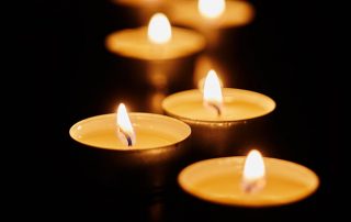 Burning votive candles on dark background - Jillian Frazin - Blessings of Jasmine