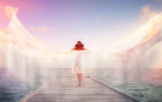 Sconceptual image of a female angel standing barefoot on an ocean jetty in a white dress with a halo and outspread wings showing motion blur with ethereal colorful sun flare effects